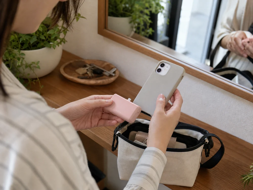 外出前にiPhoneケースとの相性を確かめるピンクの小型モバイルバッテリーのイメージ