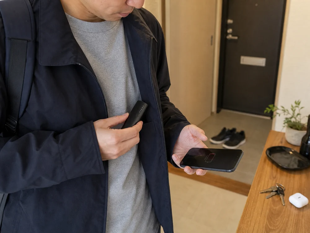 外出前に小型モバイルバッテリーを上着のポケットへ入れるシーン