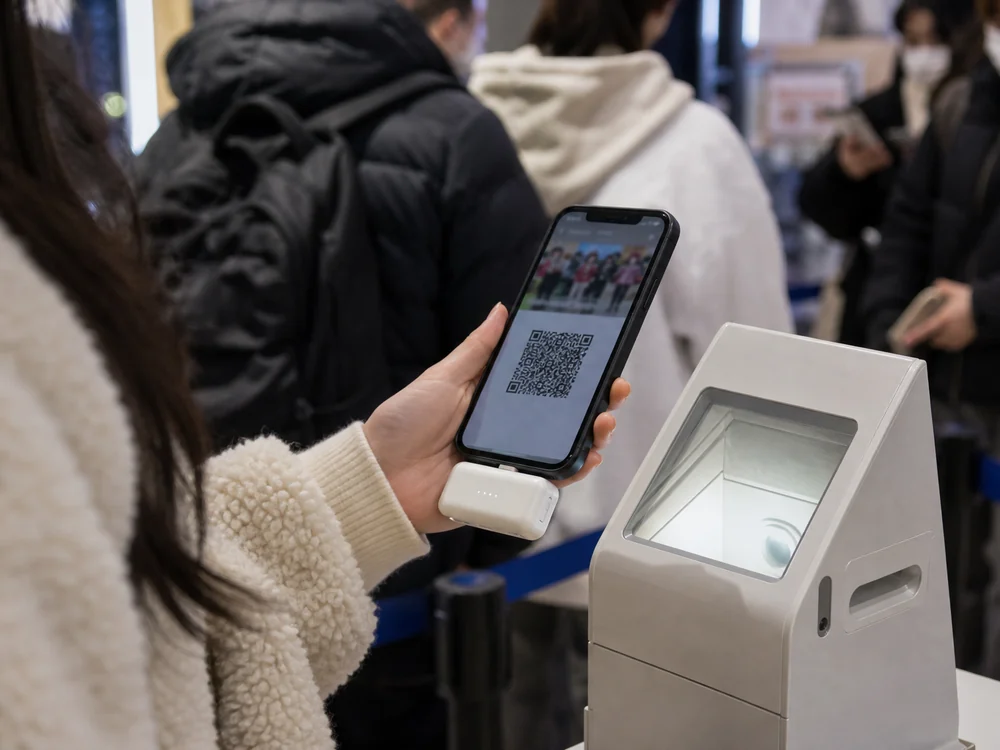 QR表示のスマホに直挿しバッテリーを付けて順番待ちする場面