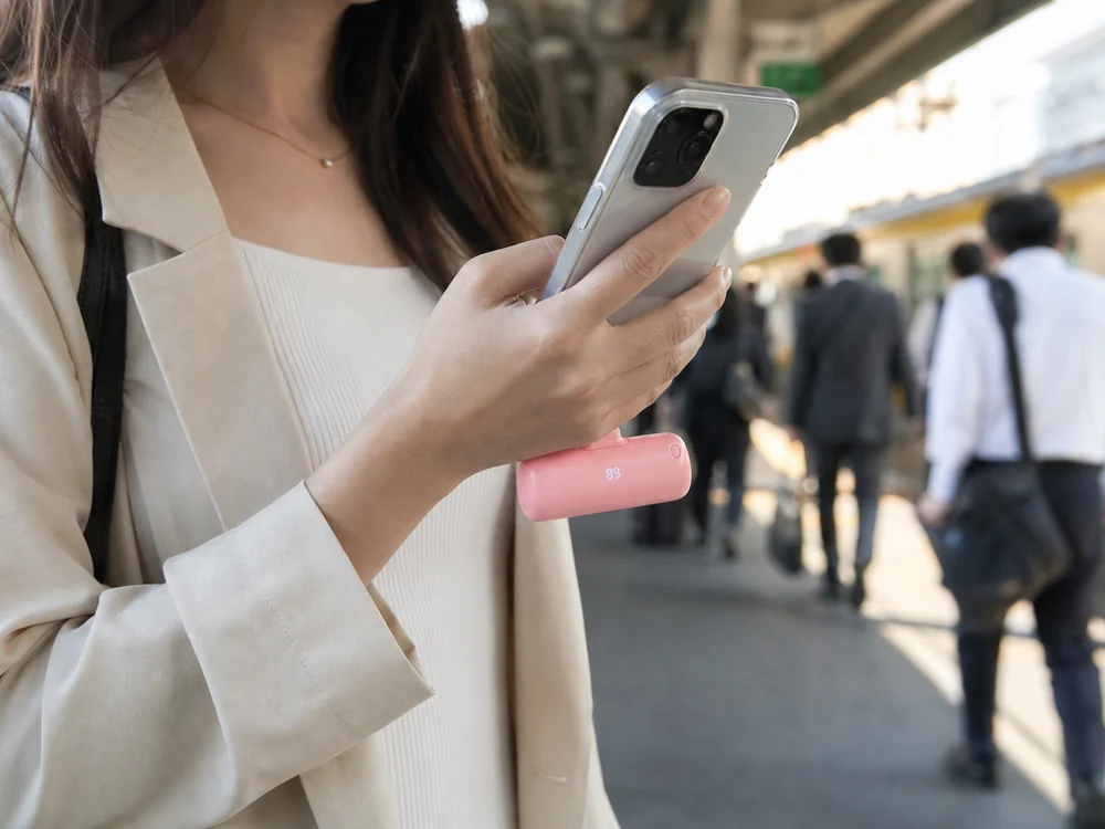 駅のホームでiWALKの一体型モバイルバッテリーをスマホに直接つないで使うイメージ