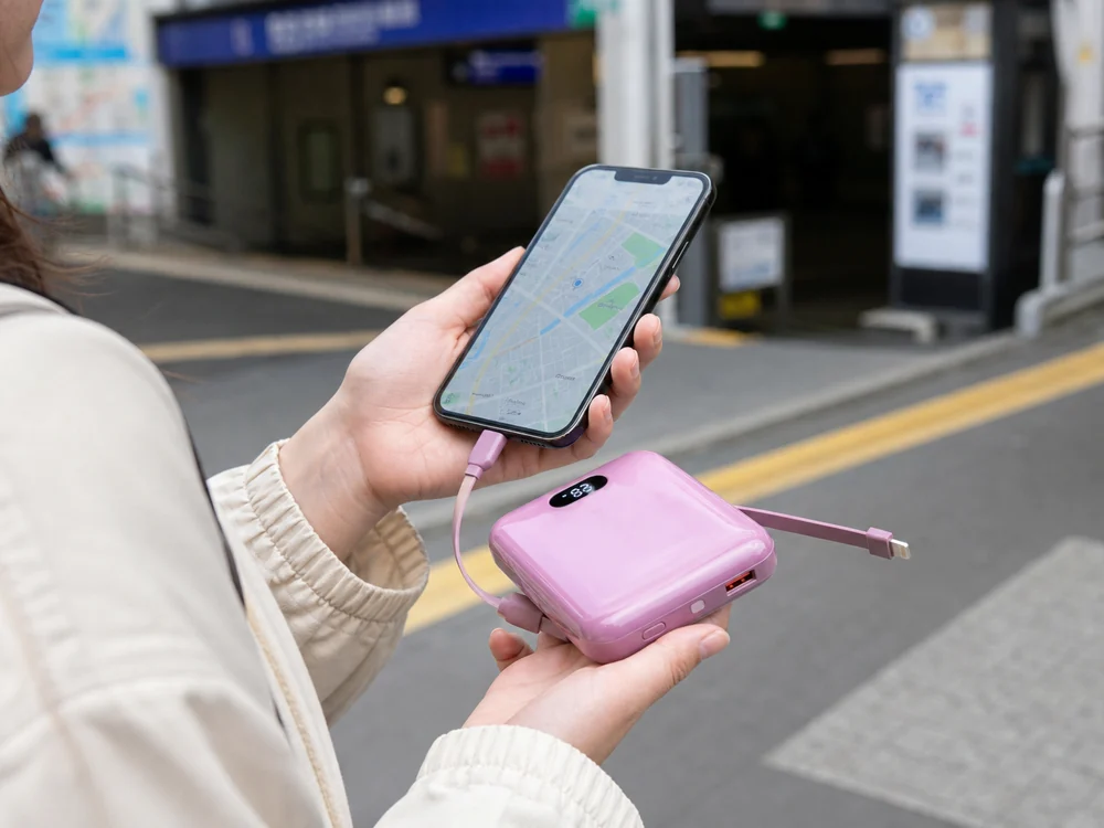 駅前で地図を見ながらPHILIPSの小型モバイルバッテリーでスマホを充電するイメージ