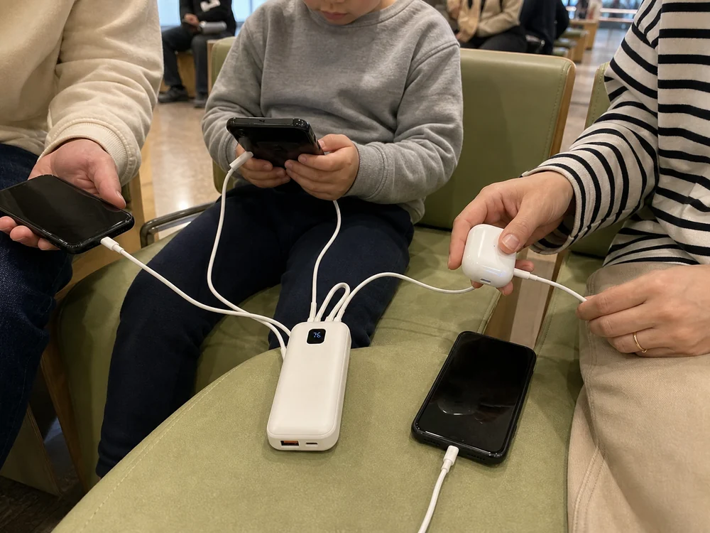 白いケーブル内蔵モバイルバッテリーで複数の端末をまとめて充電している利用シーン