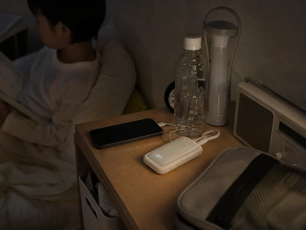 停電時の備えとして枕元に置かれた白いモバイルバッテリーの使用イメージ