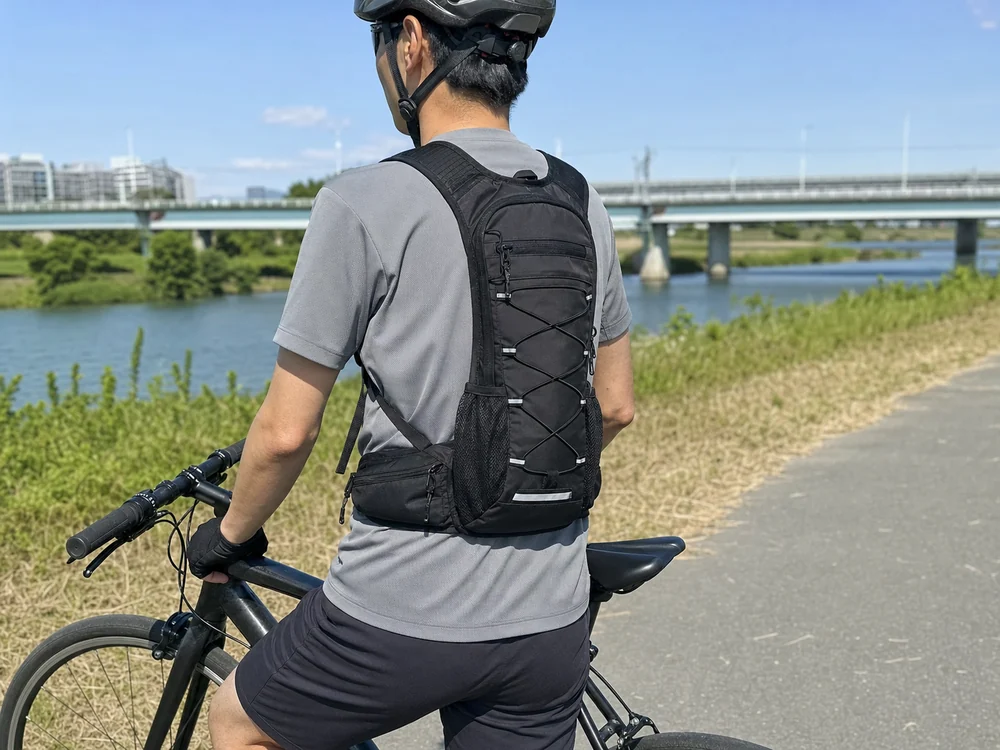 河川敷のサイクリングで黒い軽量スポーツリュックを背負う様子