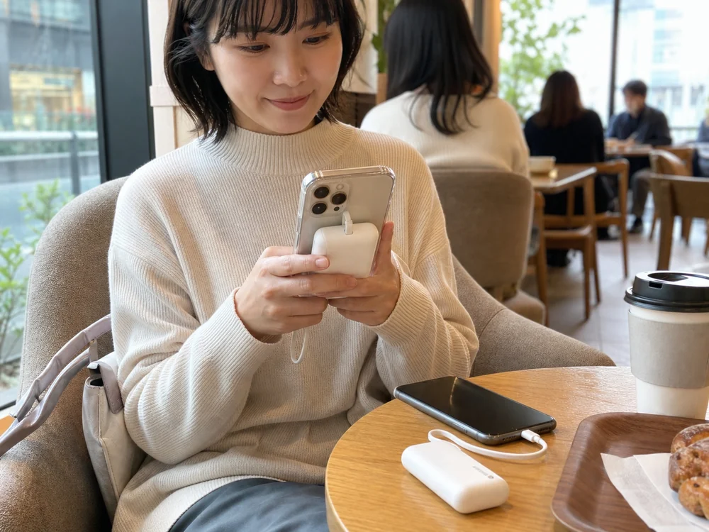 外出先でスマホを支える白い小型モバイルバッテリーのイメージ