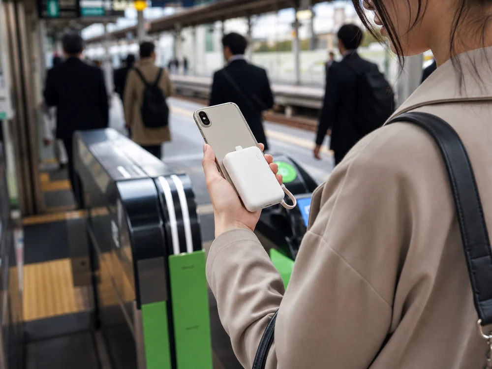 駅でスマホに直挿しして使う白い小型モバイルバッテリーのイメージ
