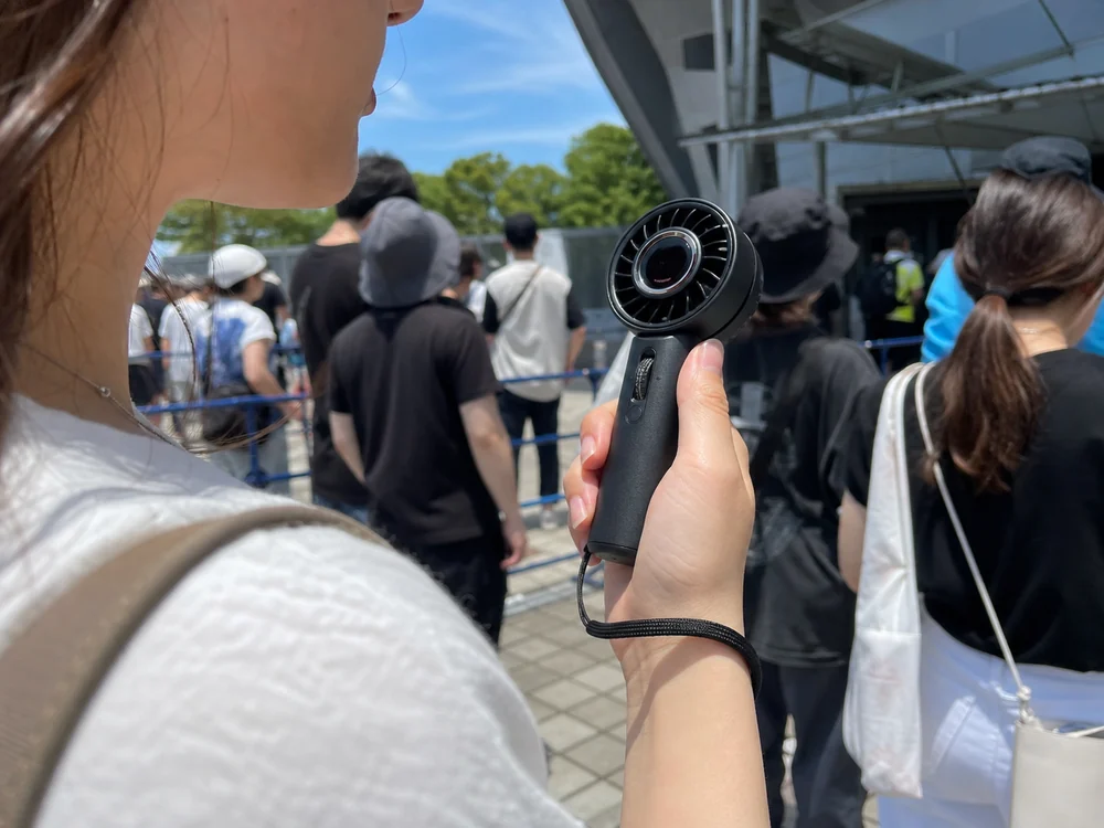 屋外の列でJISULIFE Pro1 Miniの風量を指で調整している様子