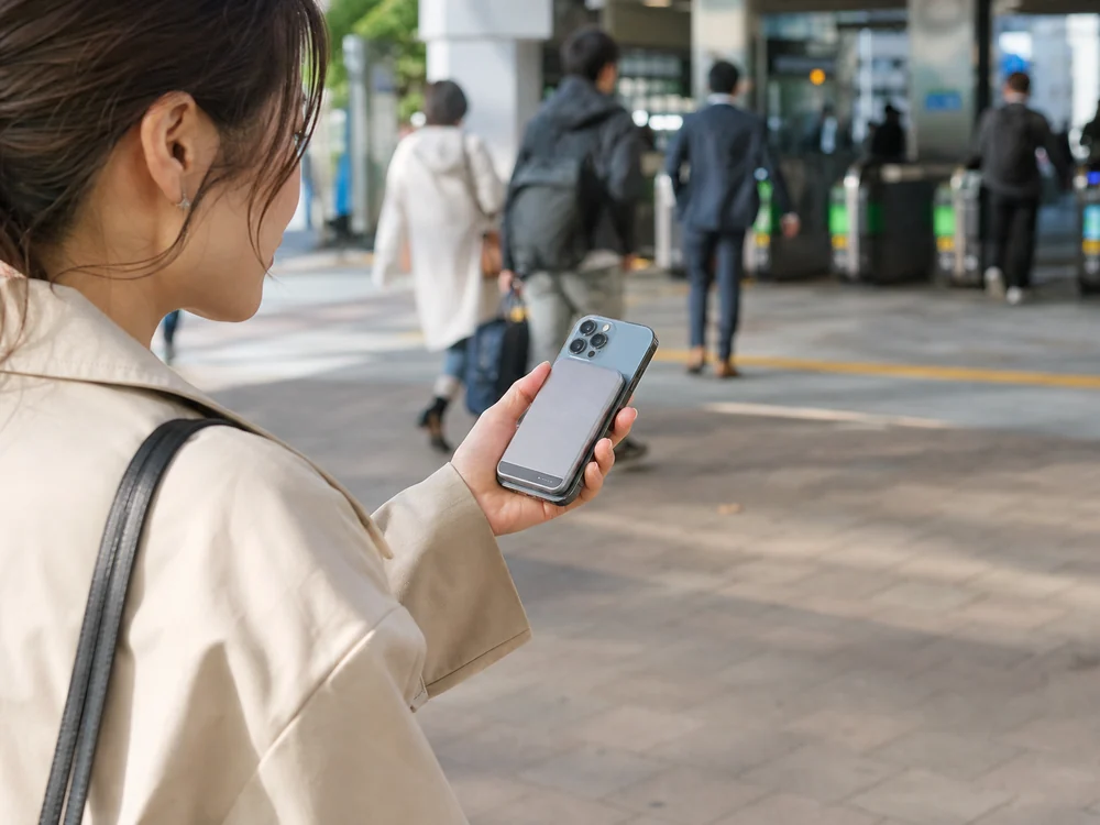 薄型のKuulaa MagSafeモバイルバッテリーを付けたiPhoneを片手で持って地図を見る様子