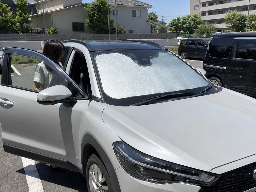 夏の駐車場でカローラクロスのフロントガラスにサンシェードを付けた状態