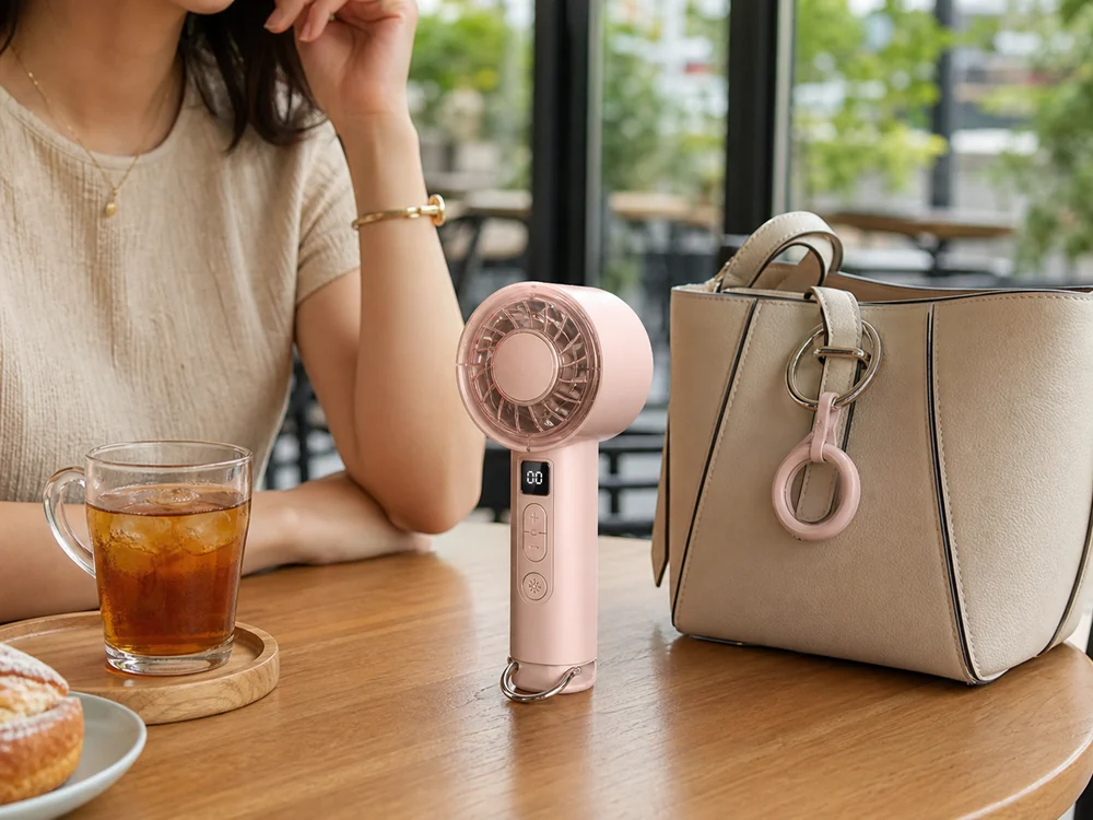 カフェで自立させたピンクの小型冷却ファンと持ち歩きやすさが分かる様子