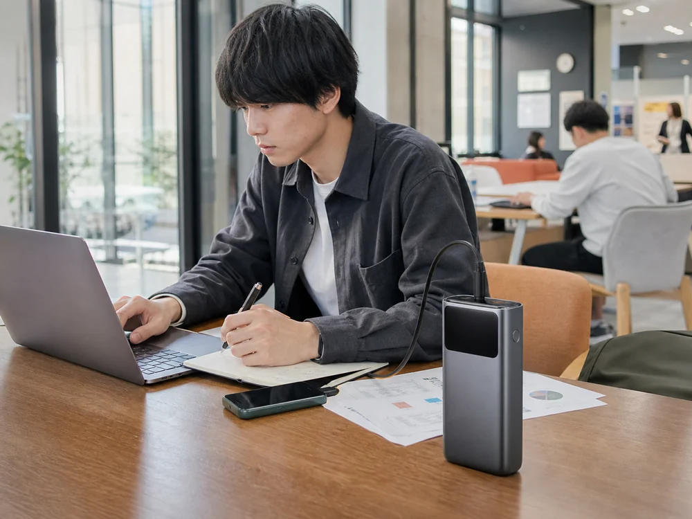 外で長時間作業する人がUGREENの高出力モバイルバッテリーを手元に置いて使うイメージ