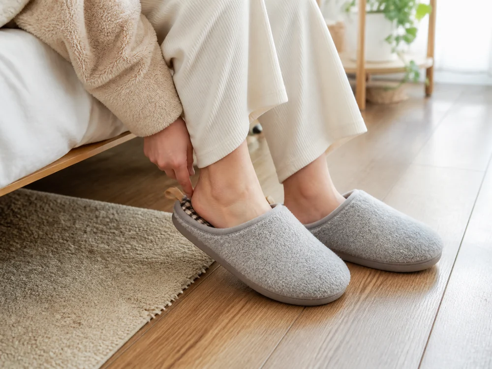 冬の朝にグレーのもこもこルームシューズへ足を入れる使用イメージ