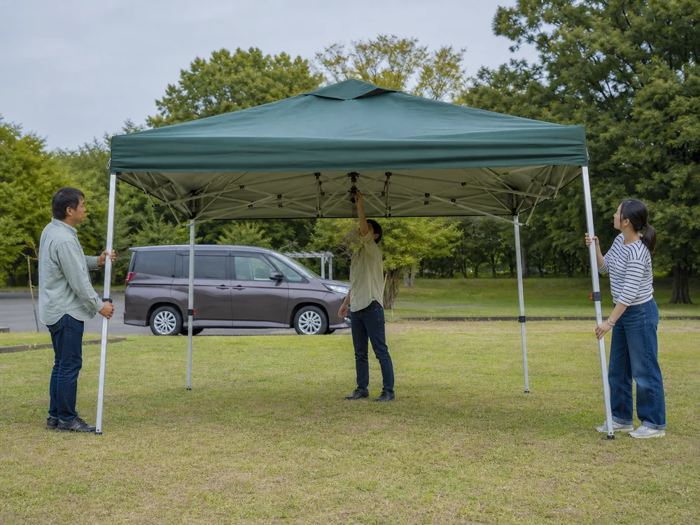 公園で大人が協力して濃緑のタープテントを設営する様子