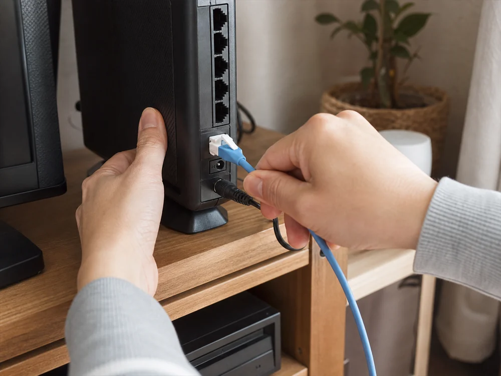 ルーター交換時に青いLANケーブルの白いツメを押して抜き差しする様子