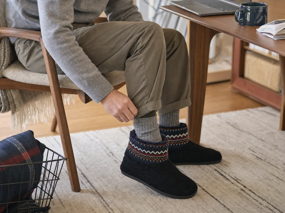厚手の靴下と濃紺のブーツ型ルームシューズを合わせる男性