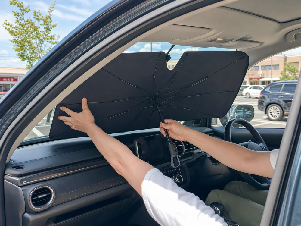 夏の駐車場で車内に傘型サンシェードを広げる様子