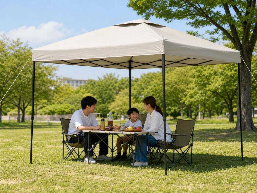 芝生の公園で家族のテーブルに日陰を作るライトベージュのワンタッチタープ