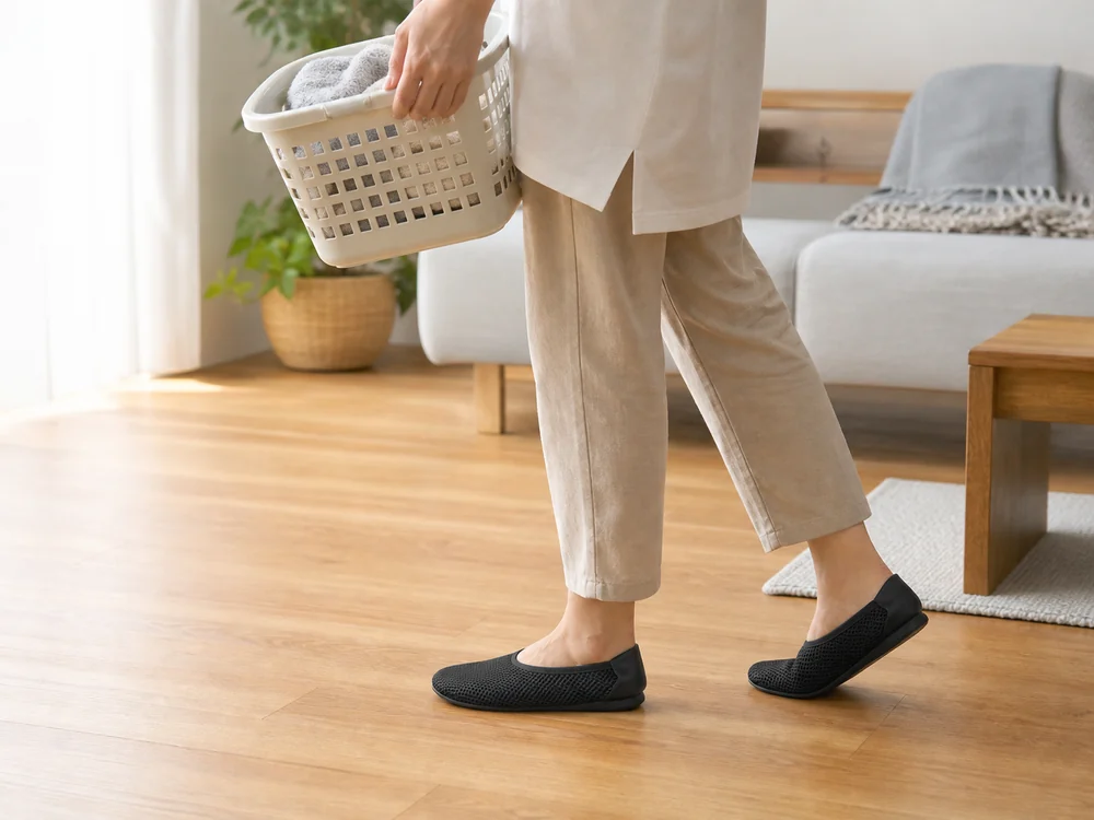 黒いメッシュのおうちスリッポンを履き、洗濯かごを運ぶ室内の様子