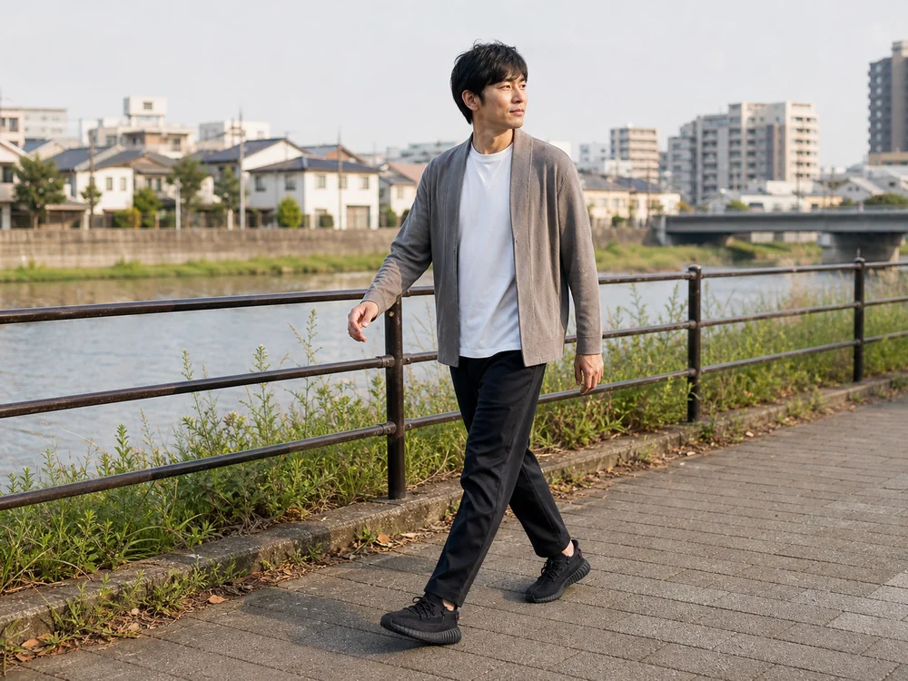 川沿いの舗装路を黒いメッシュスニーカーで歩く人
