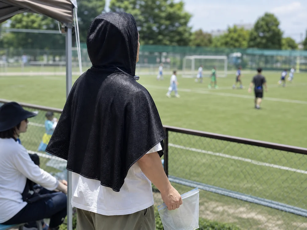 夏のサッカー付き添いで黒い冷感ポンチョを羽織る保護者