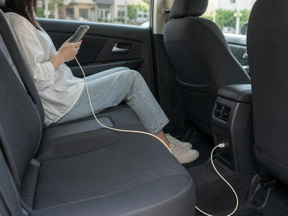 車の後部座席でiPhoneにつないだアーモンドミルク色のLightningケーブルが前席側のUSB-Aポートまで届いている様子