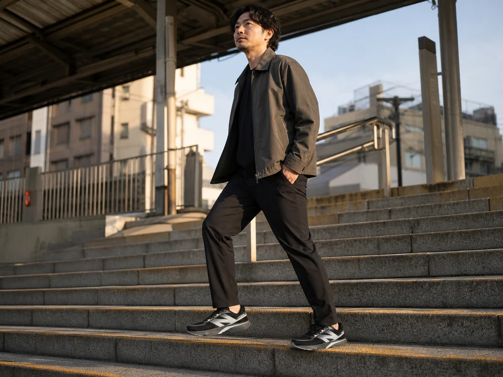 黒いパンツと黒とシルバーのランニングシューズで街の階段を上る人