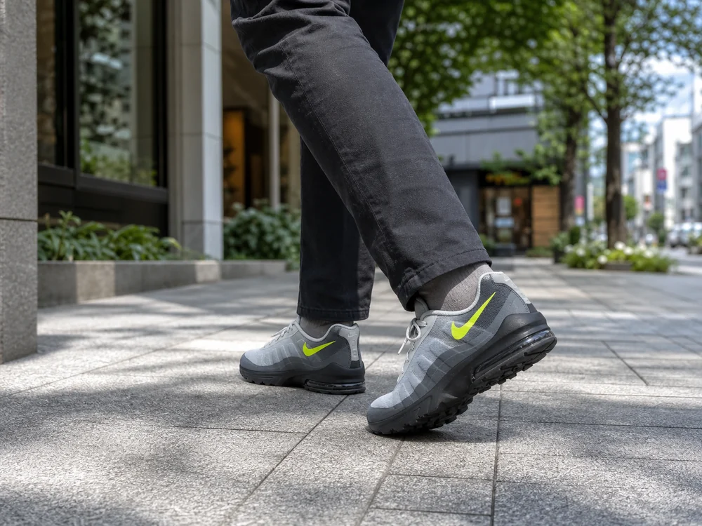 日本の街路でグレーと黒のエアクッションスニーカーを履いて歩く足元