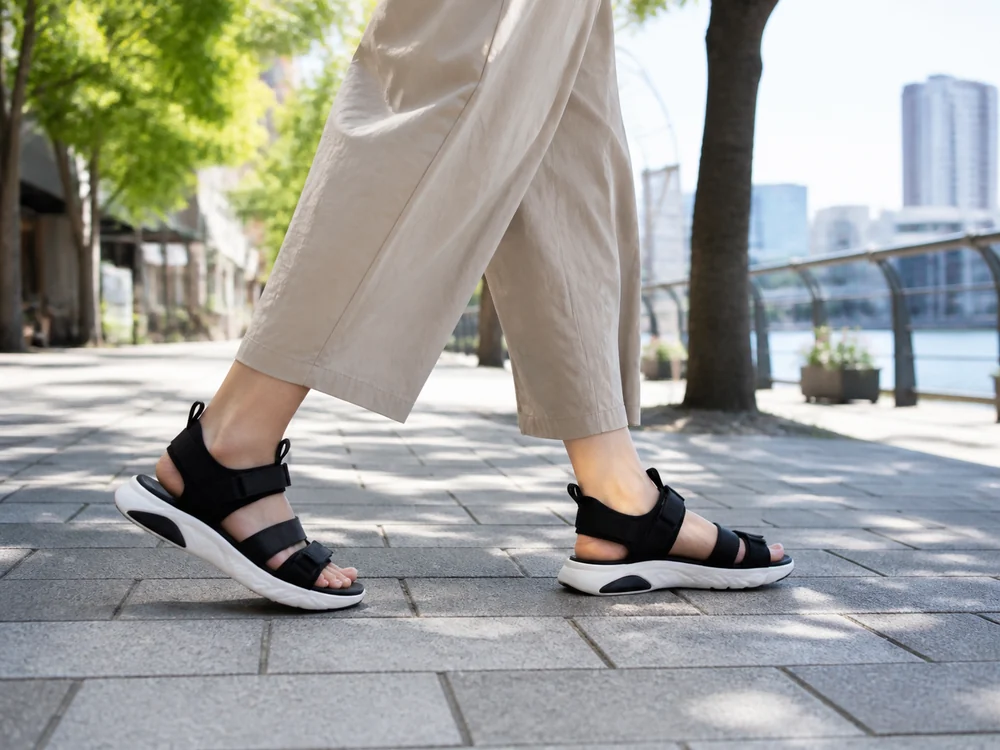 白い厚底ソールの黒いスポーツサンダルで夏の街歩きをする様子