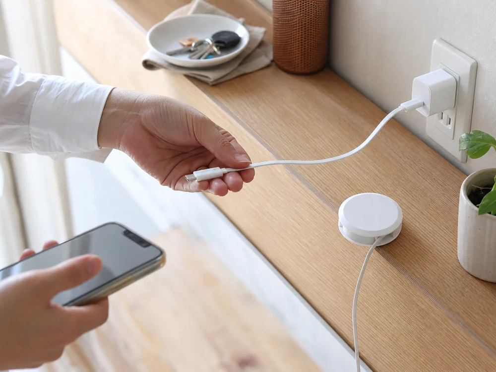 白い巻取り式USB-Cケーブルをスマートフォンの充電準備で引き出す様子