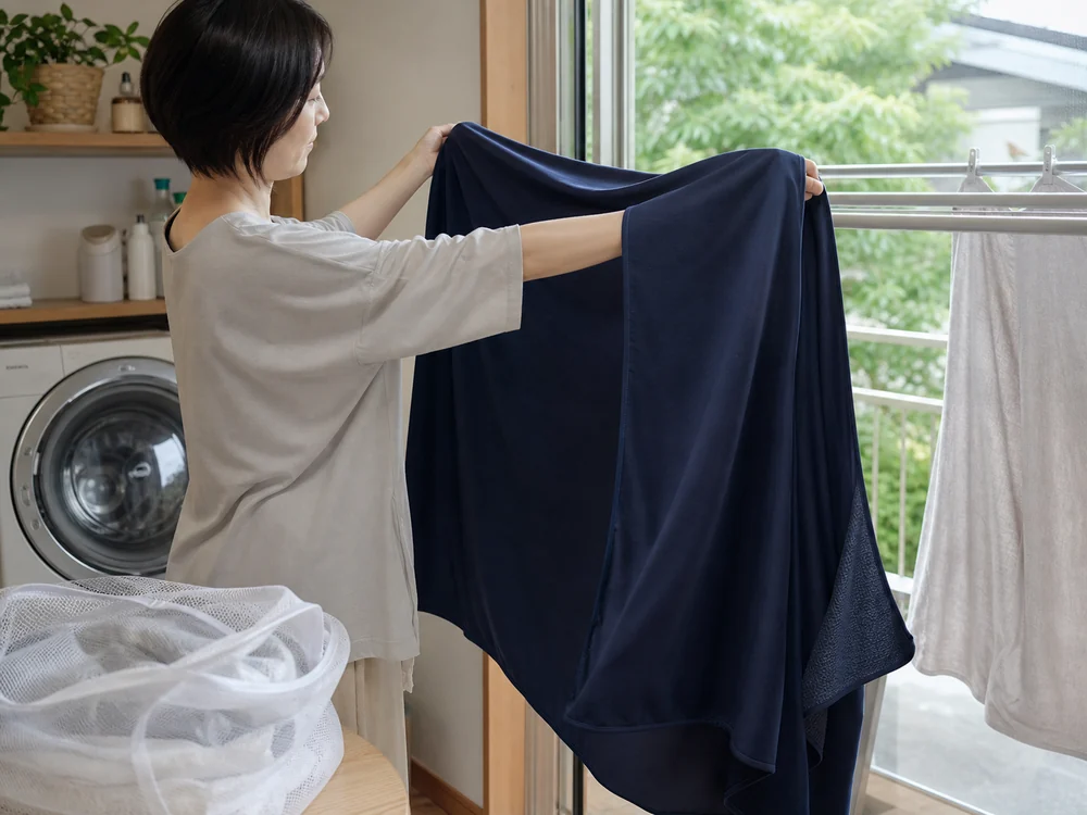 洗濯した濃紺の冷感タオルケットを室内で陰干しする様子