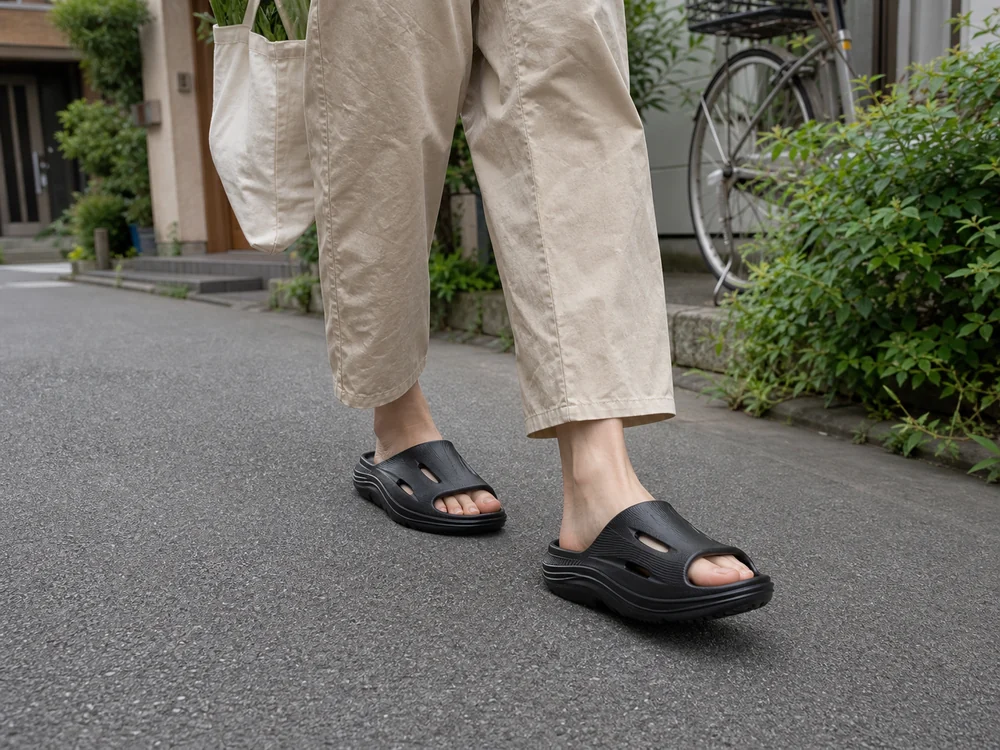 黒いリカバリーサンダルで近所の舗装路を短く歩く足元