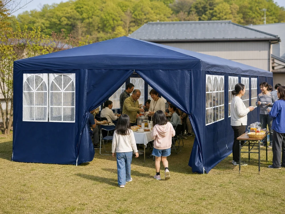 青い側壁付きパーティーテントで地域の軽食会を楽しむ人たち