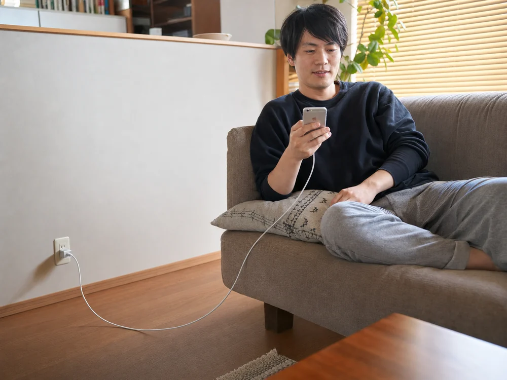 ソファで2mの銀色ライトニングケーブルを使いiPhoneを充電する様子