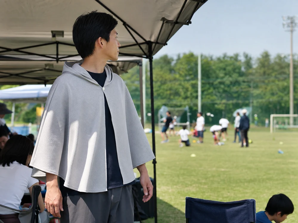 夏の屋外イベントでフード付き冷感ポンチョを羽織る大人