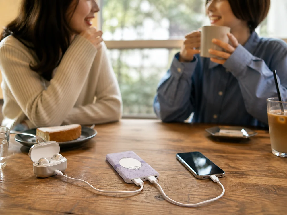 ラベンダー色のモバイルバッテリーでスマートフォンとイヤホンを同時充電している様子