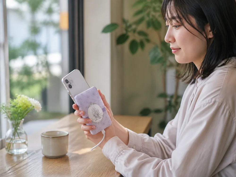 カフェで薄型ラベンダー色のモバイルバッテリーからスマートフォンを充電している様子