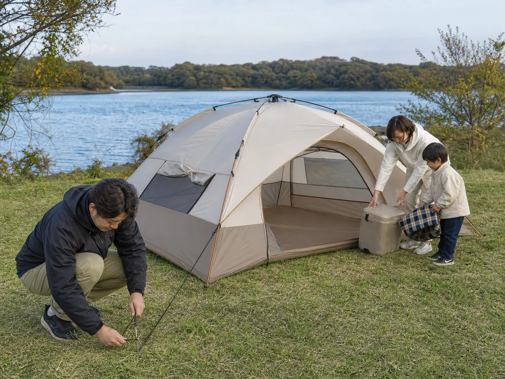 湖畔でロープとペグを使いワンタッチテントを固定する家族